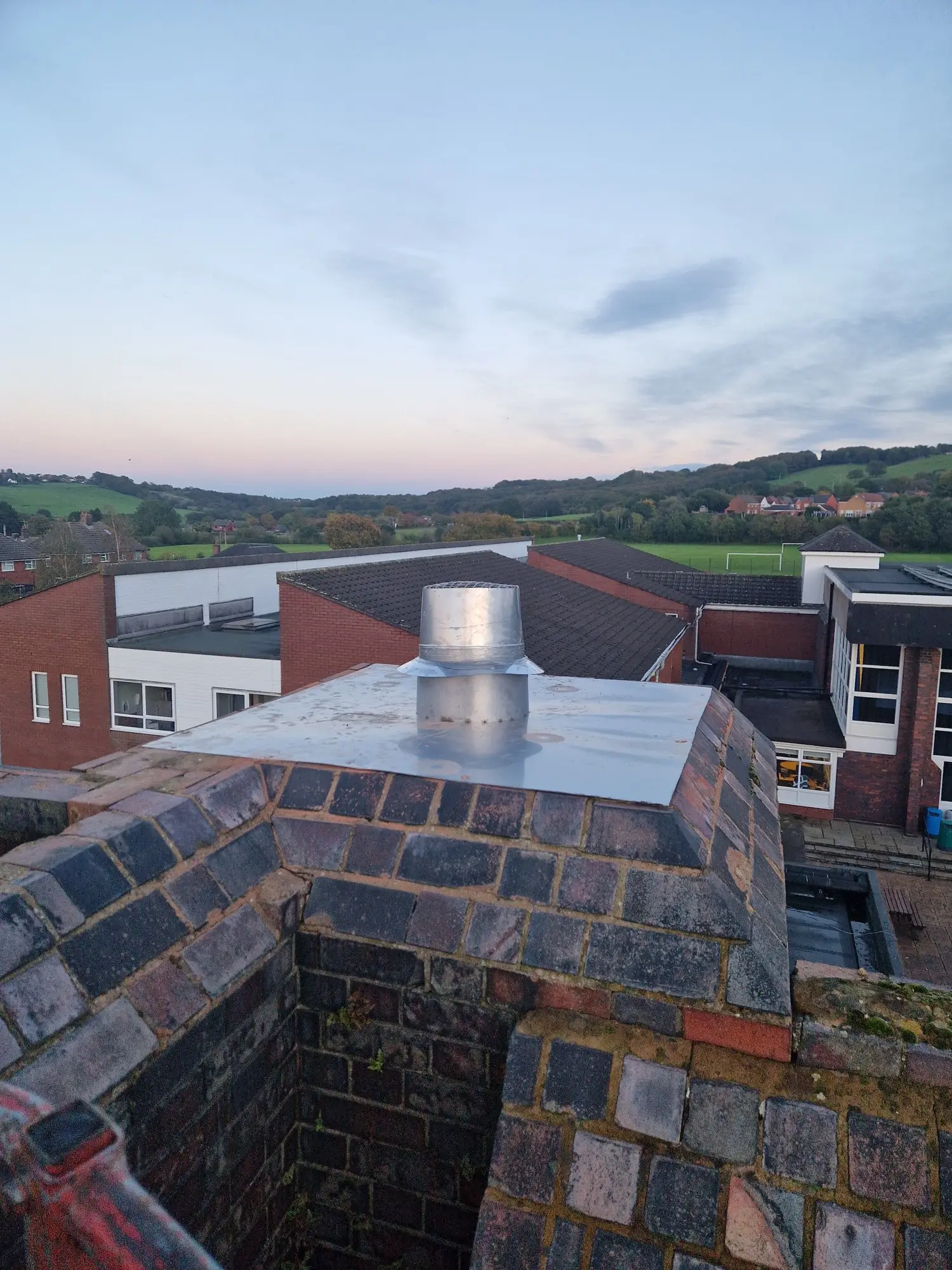 Flexible liner terminal on top of the school brick chimney at dusk