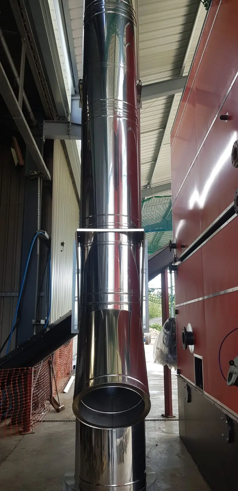 Twin wall insulated flue rising from a biomass boiler in a plant room