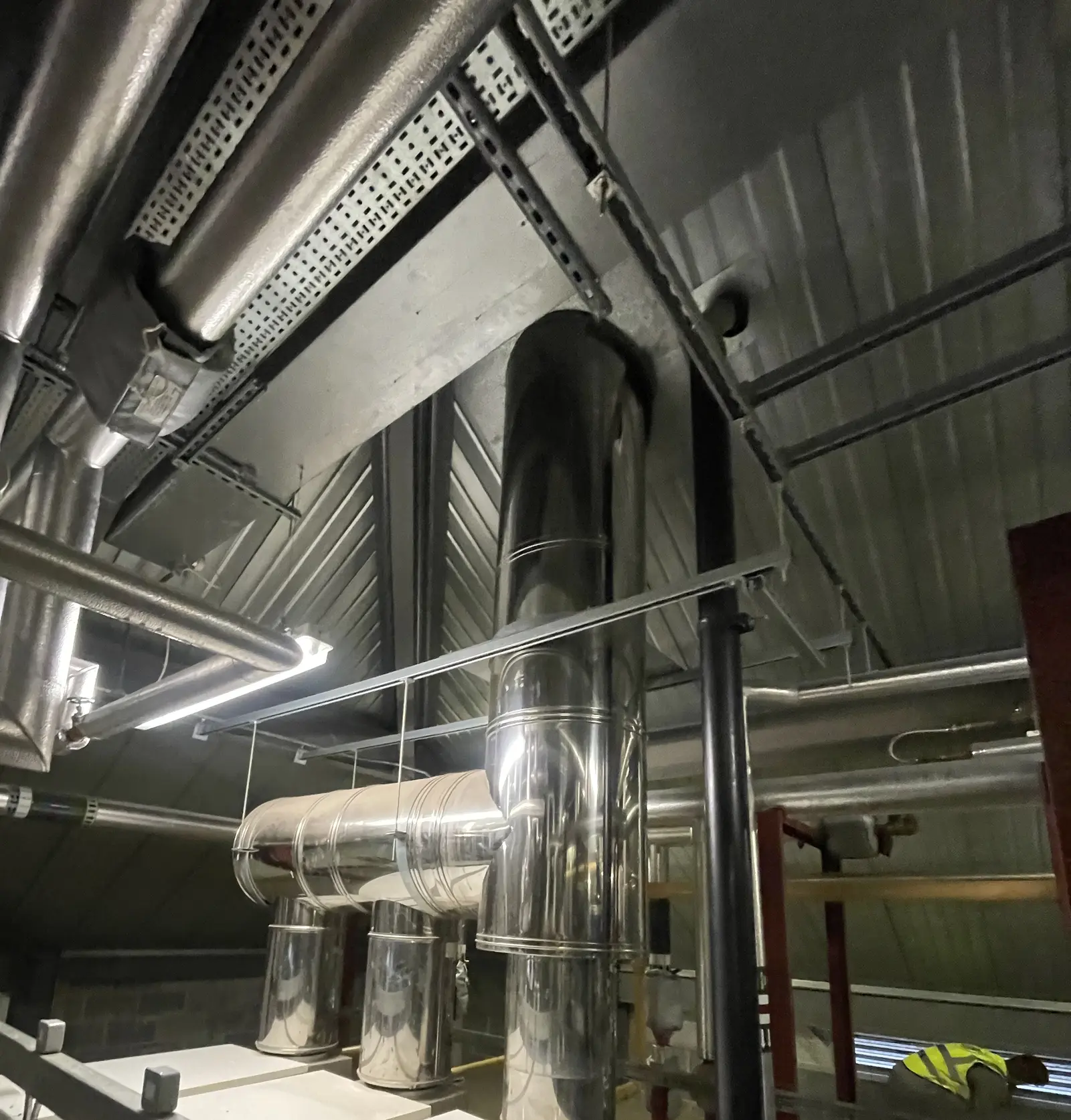 Stainless boiler flue header with tees off each boiler and a riser in a hospital plantroom