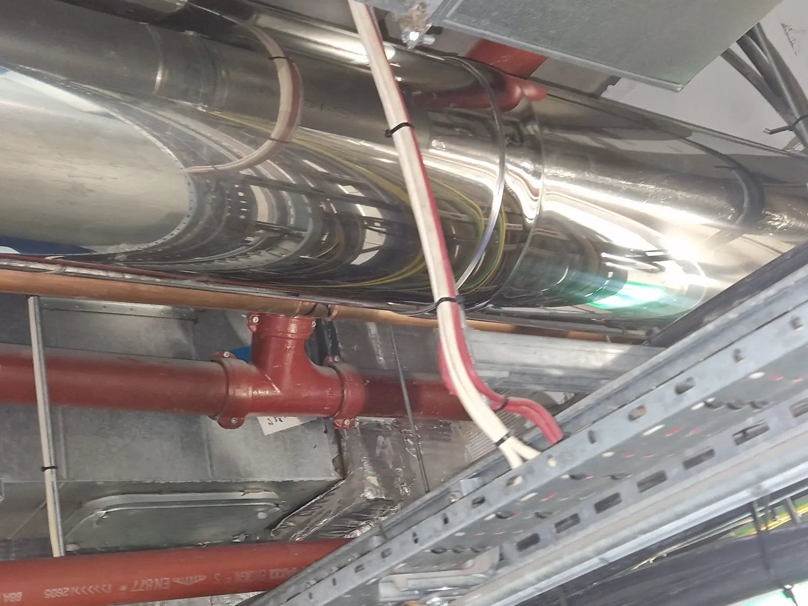Long horizontal stainless flue run at ceiling level along a corridor