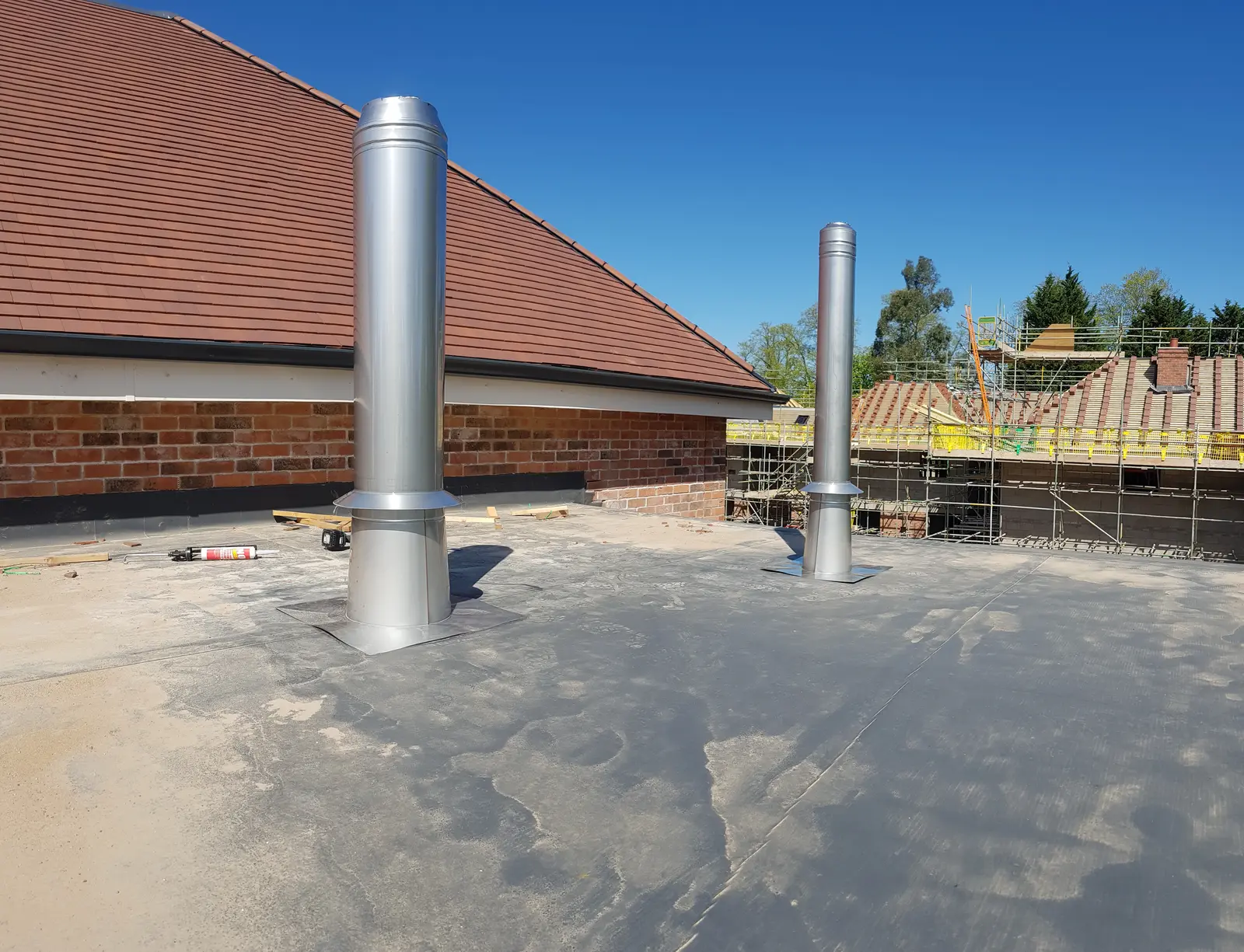 Two large stainless steel stacks on a roof, installed by Grün